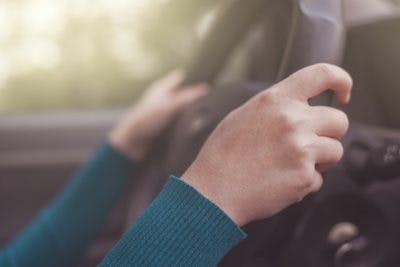 up close shot of womans hands on steering wheel