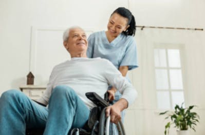 caregiver smiling at stroke patient in wheelchair