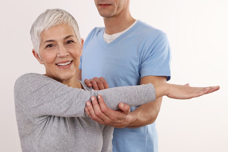 physiotherapist helping a stroke survivor with arm mobility after her symptoms started getting worse