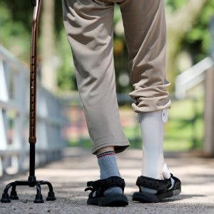 man walking with foot drop brace and four-prong cane