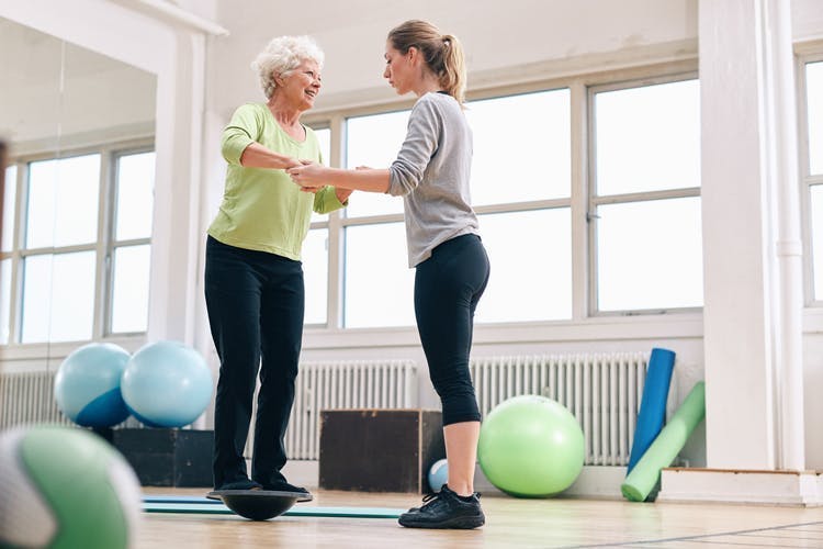 Une soignante aide une patiente atteinte d'AVC à effectuer des exercices de l'équilibre.