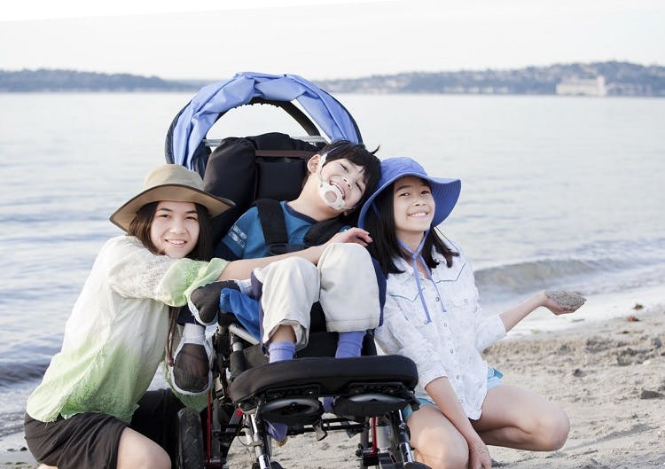 child with a type of cerebral palsy called spastic quadriplegia at the beach with family