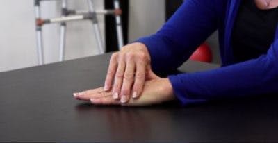 L'ergothérapeute pose la main gauche sur la table, paume en bas, pour commencer l'exercice.