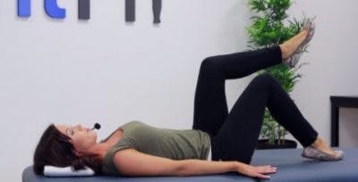 La physiothérapeute allongée plie les genoux à 90 degrés pour vous montrer le début de l’exercice.  