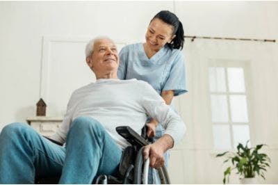 Une soignante aide un patient qui est assis sur un fauteuil roulant à commencer à faire face aux effets secondaires de son AVC.
