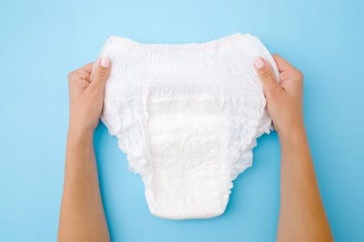 person holding up absorbent underwear to manage loss of bladder control after brain injury