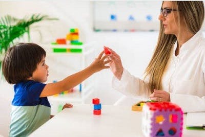 child with ataxic cp working with a therapist to improve fine motor skills