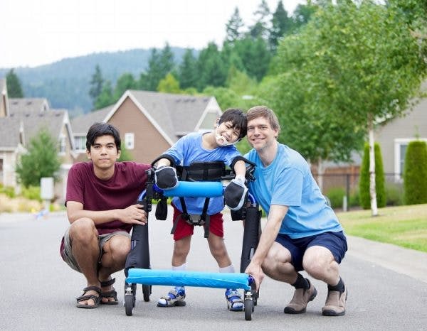 由于脑瘫而使用助行器行走的男孩，行走方式异常，称为蹲伏步态