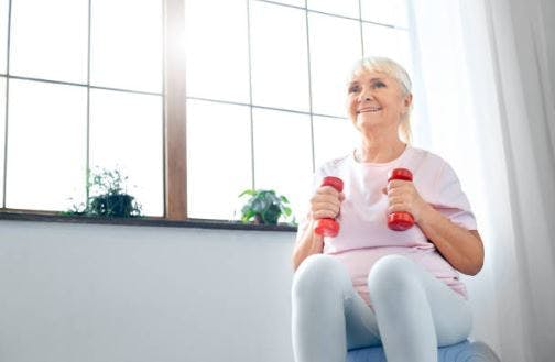 patient d'AVC faisant de l'exercice à la maison avec un ballon médicinal et des haltères