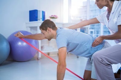 Therapeut, der Hemiplegiepatienten beim Training in der Physiotherapieklinik hilft