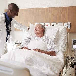 friendly doctor talking to bedridden stroke patient