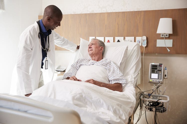 friendly doctor talking to bedridden stroke patient