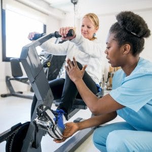physiotherapist helping patient with hemiplegia use stationary bike