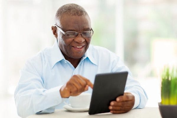 homme âgé faisant des exercices de rééducation cognitive sur tablette pour améliorer la mémoire après un AVC