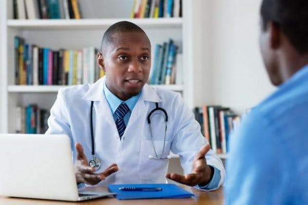 médecin assis au bureau parlant à un patient victime d'un AVC du lobe pariétal de la rééducation