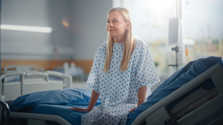 woman at the edge of the hospital bed waiting patiently for the doctor to tell her what to expect after brain injury