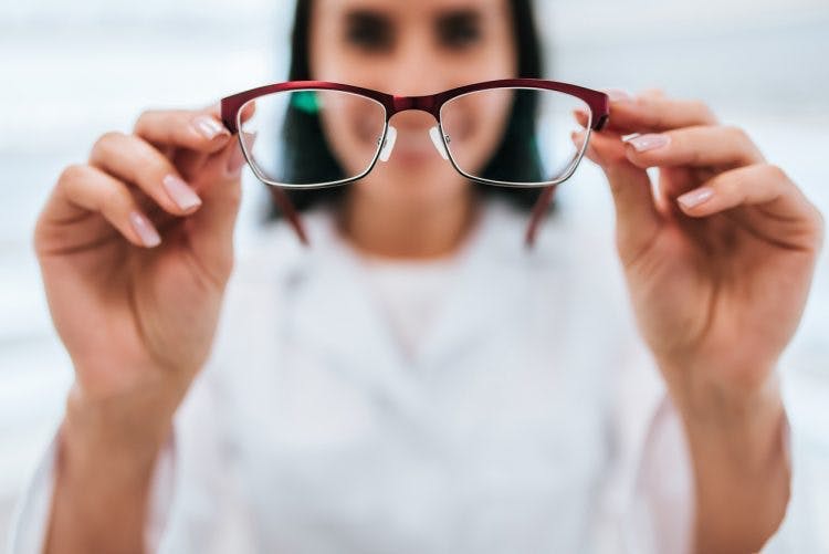 Frau hält eine Brille hoch, um das Sehvermögen nach einem Schlaganfall zu verbessern