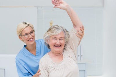 physical therapist lifting up a stroke survivor's arm for CIMT, a popular stroke rehabilitation technique