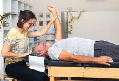 therapist lifting a stroke survivor's arm up to perform passive exercise for stroke recovery treatment