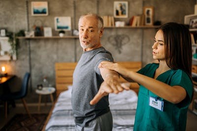 brain injury patient does arm exercises with physical therapist in home setting