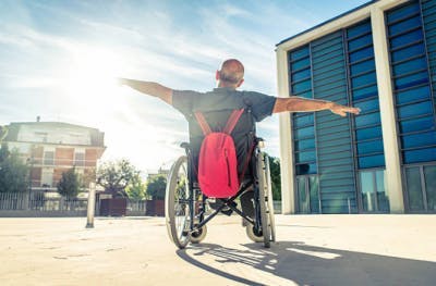 Un survivant d'AVC sur un fauteuil roulant, à bras ouvert, embrace la journée en pleine soleil pour symboliser que même une paralysie, qui peut s'avérer temporaire, n'empêchera pas sa récupération.