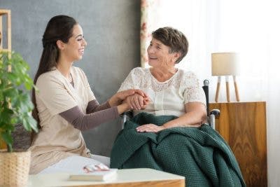 a respite care nurse holds hands with an individual with quadriplegia at home