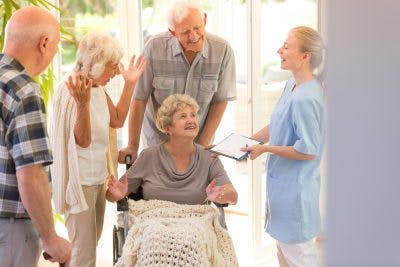 stroke survivor in wheelchair preparing to leave the hospital with family members and a nurse surrounding her cheerfully