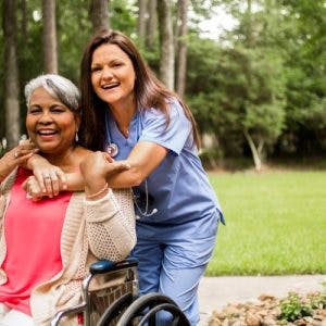 护理人员拥抱坐在轮椅上的妇女，显示出贯穿生命各个阶段的脑瘫症状和体征