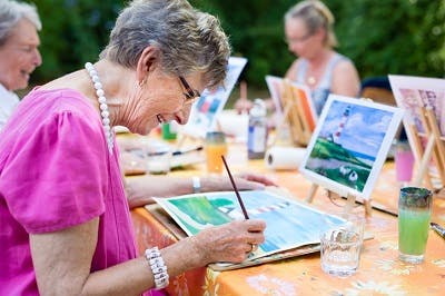 side view of women having fun engaging in activities for brain injury patients such as painting