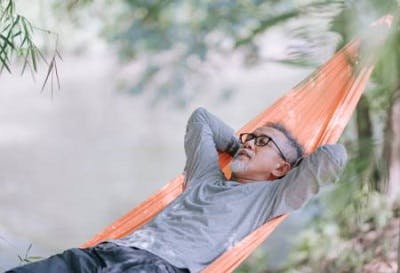 man sitting in a hammock with his eyes closed to get some cognitive rest and improve post concussion symptoms naturally