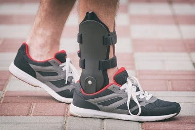 person with AFO brace for foot drop showing underneath his sneakers as he takes a step forward