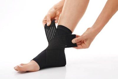 person wrapping a soft AFO brace for foot drop around ankle using big velcro strips