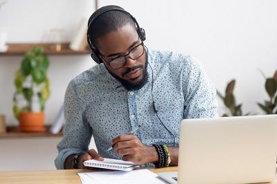 man with headphone and notepad using a speech and cognitive therapy app to improve aphasia after brain injury