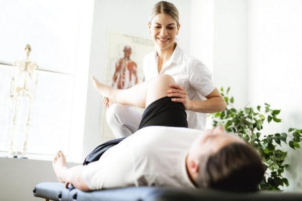 Physiotherapeut hilft Person bei Bewegungsübungen für Schlaganfallpatienten mit Lähmungen