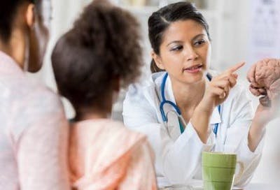 doctor points to model of human brain while explaining to child with traumatic brain injury how recovery works