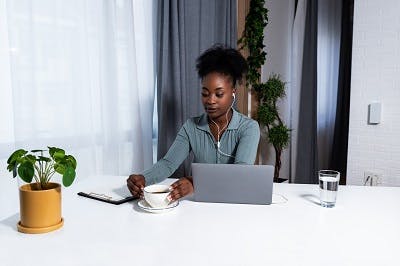 woman sitting down attempting to lift her coffee and restore hand function after basal ganglia brain damage