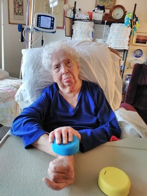 Margaret in her hospital bed using the FitMi pucks to exercise