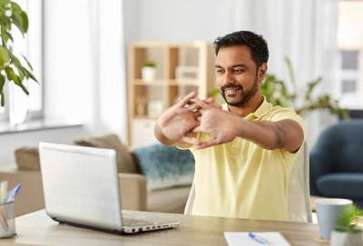 man sitting on his desk practicing stretching upper body exercises after sci