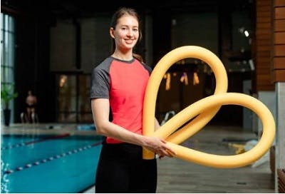 physical therapist showing noodles to survivors to use in aquatic therapy for spinal cord injury