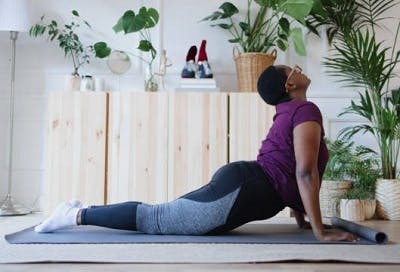 Individual practicing the cobra stretch at home, a mat exercise for spinal cord injury.