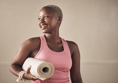 Survivor happily carrying her exercise mat for spinal cord injury rehabilitation.