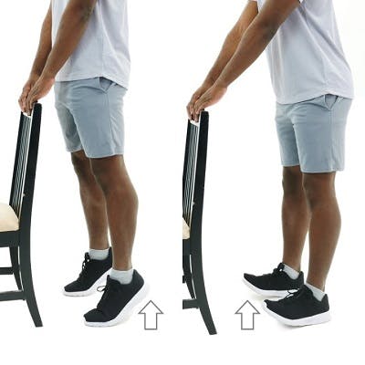 man standing on his tip-toes while holding the back of a chair for stability