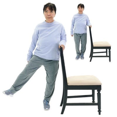 woman standing next to chair and lifting outside leg out to the side for walking exercises for stroke patients