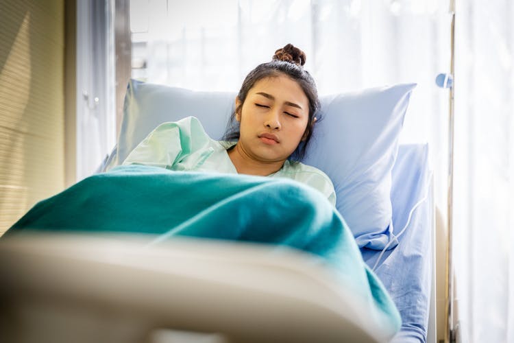 Frau im Krankenhausbett, die sich nach einer Kopfverletzung übel fühlt